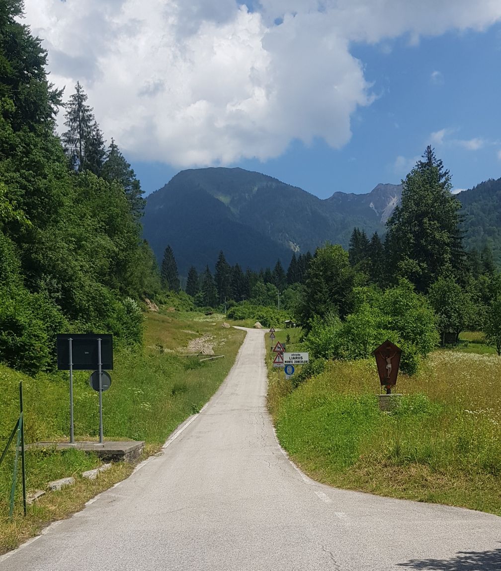 Zoncolan begin klim buiten dorp Liariis met uitzicht berg en bos